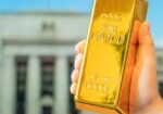 Gold bar held in front of the Federal Reserve building illustrating the Fed impact on gold prices